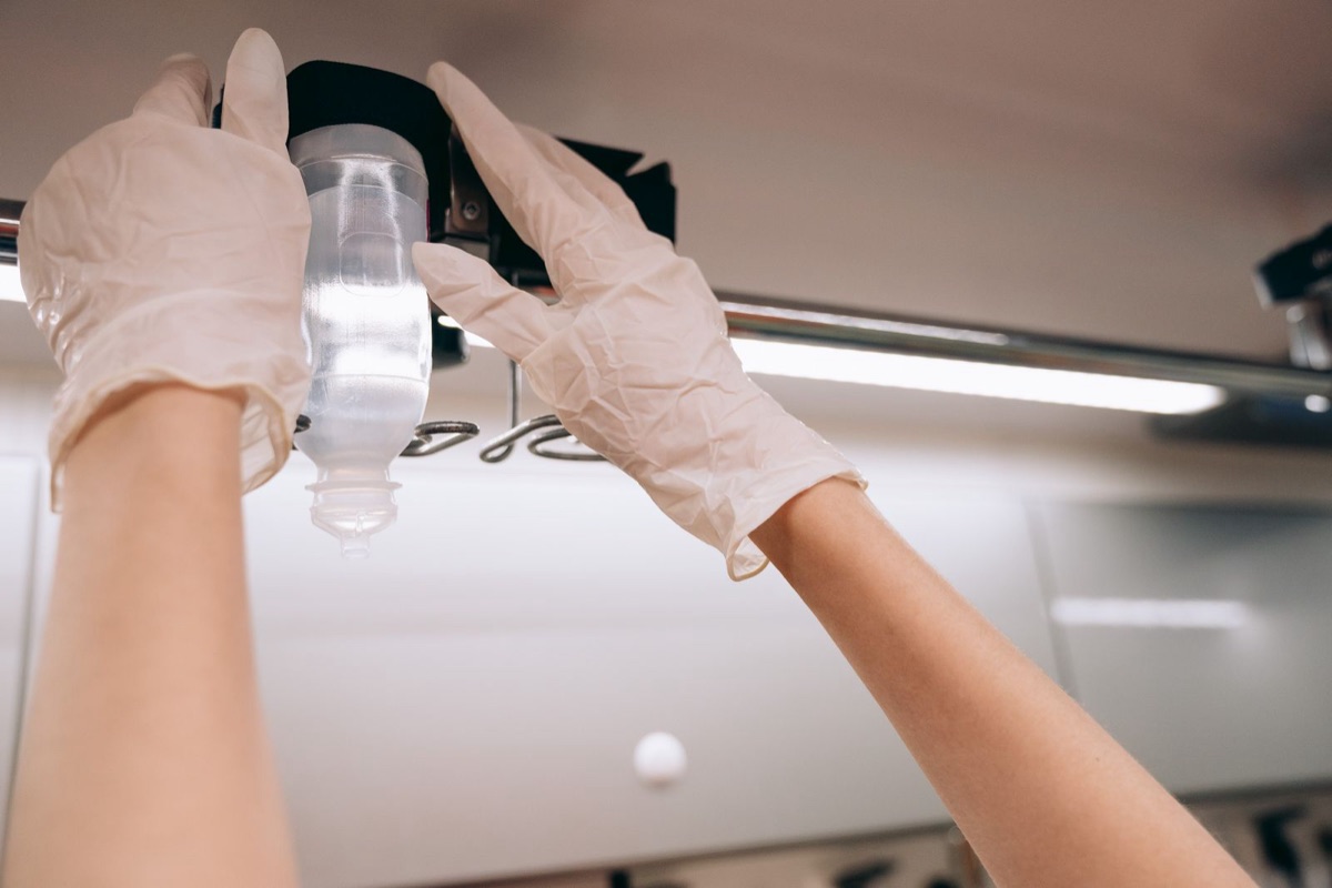 Gloved hands adjusting an IV line